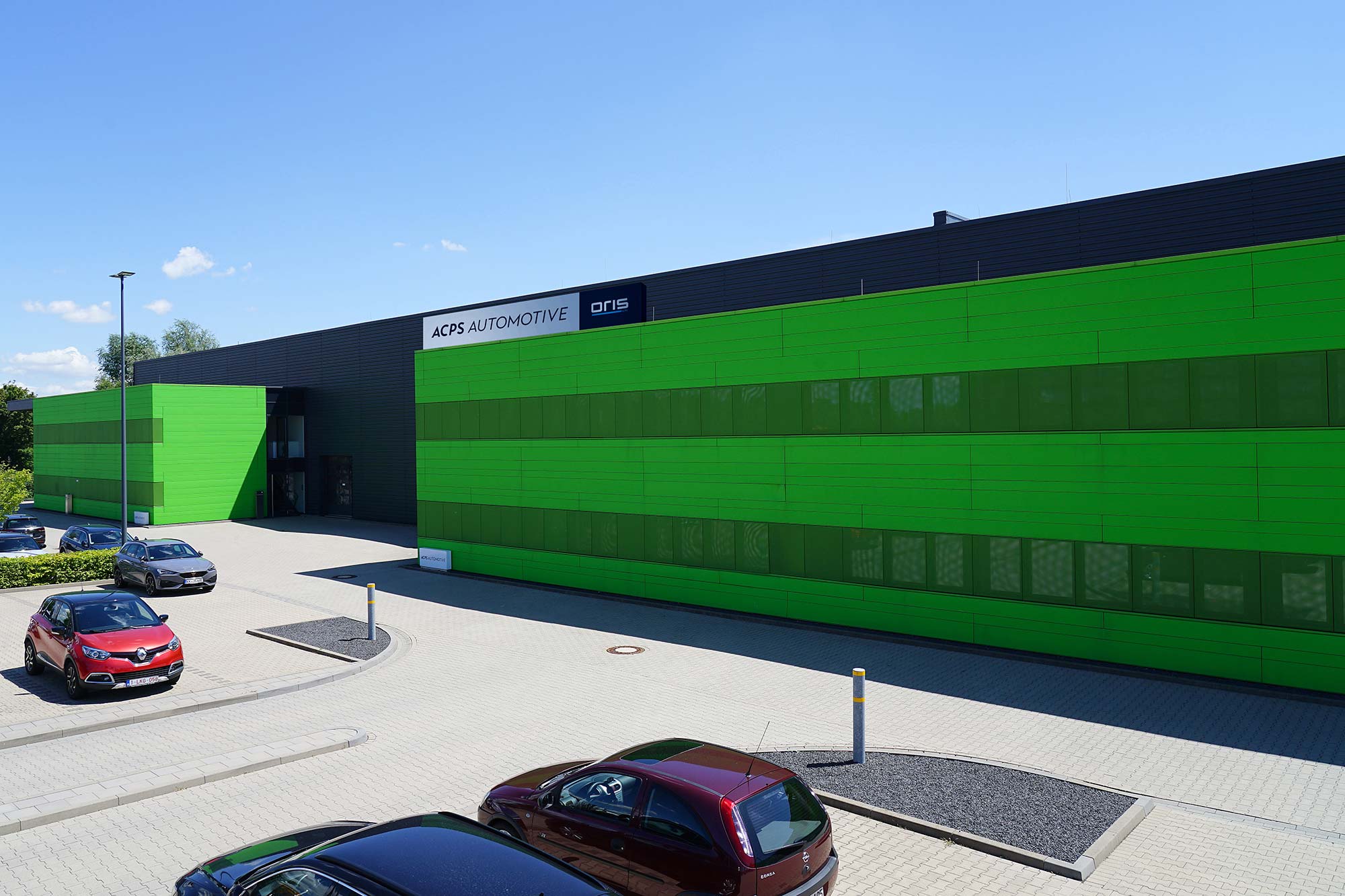 ACPS Automotive building with ORIS sign, green facade and parked cars in the courtyard at the Mönchengladbach location.