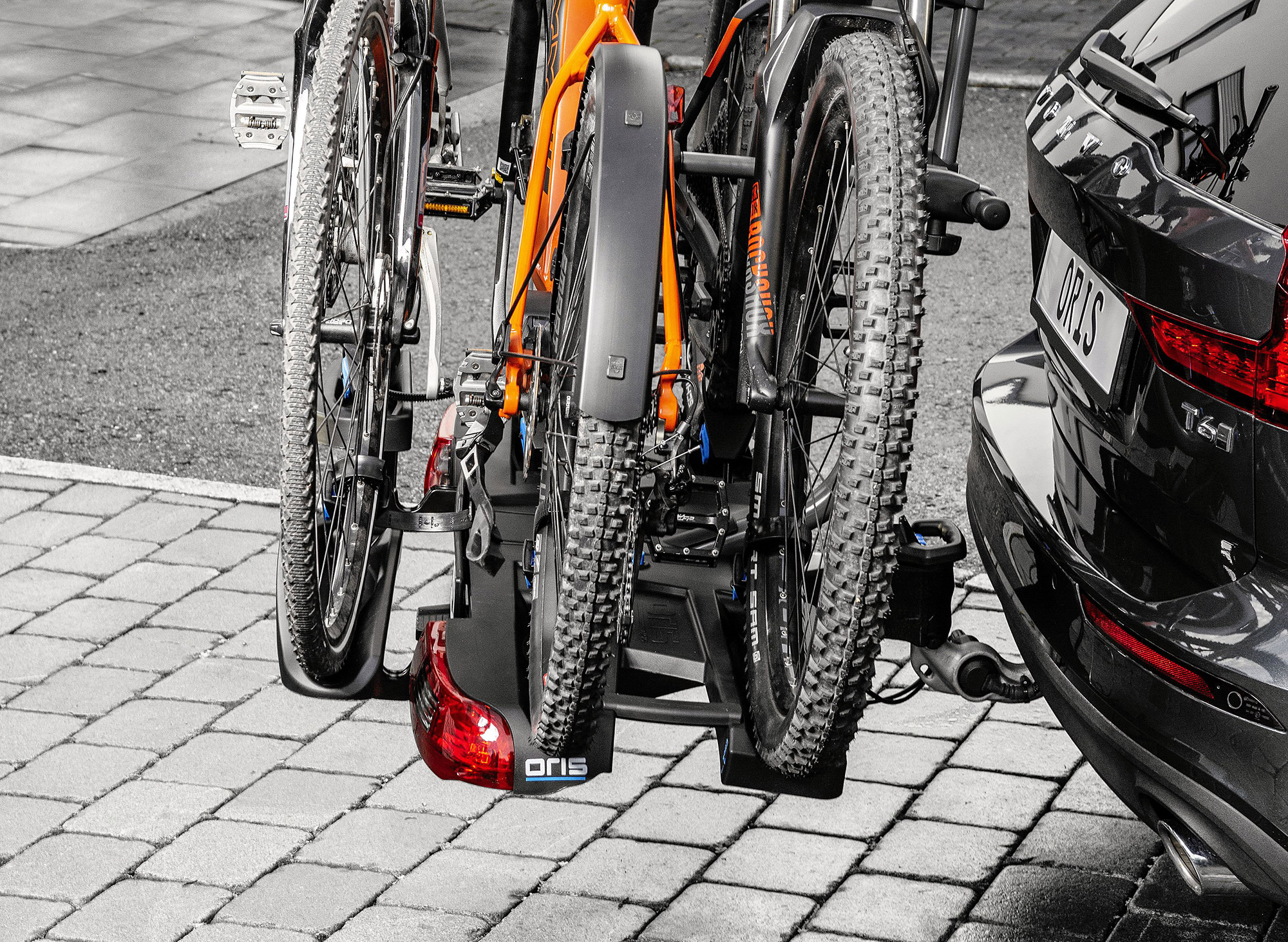 Close-up of the ORIS TRACC bike carrier mounted on an ORIS E3 swivelling towbar, carrying three bicycles on the rear of a black Volvo.