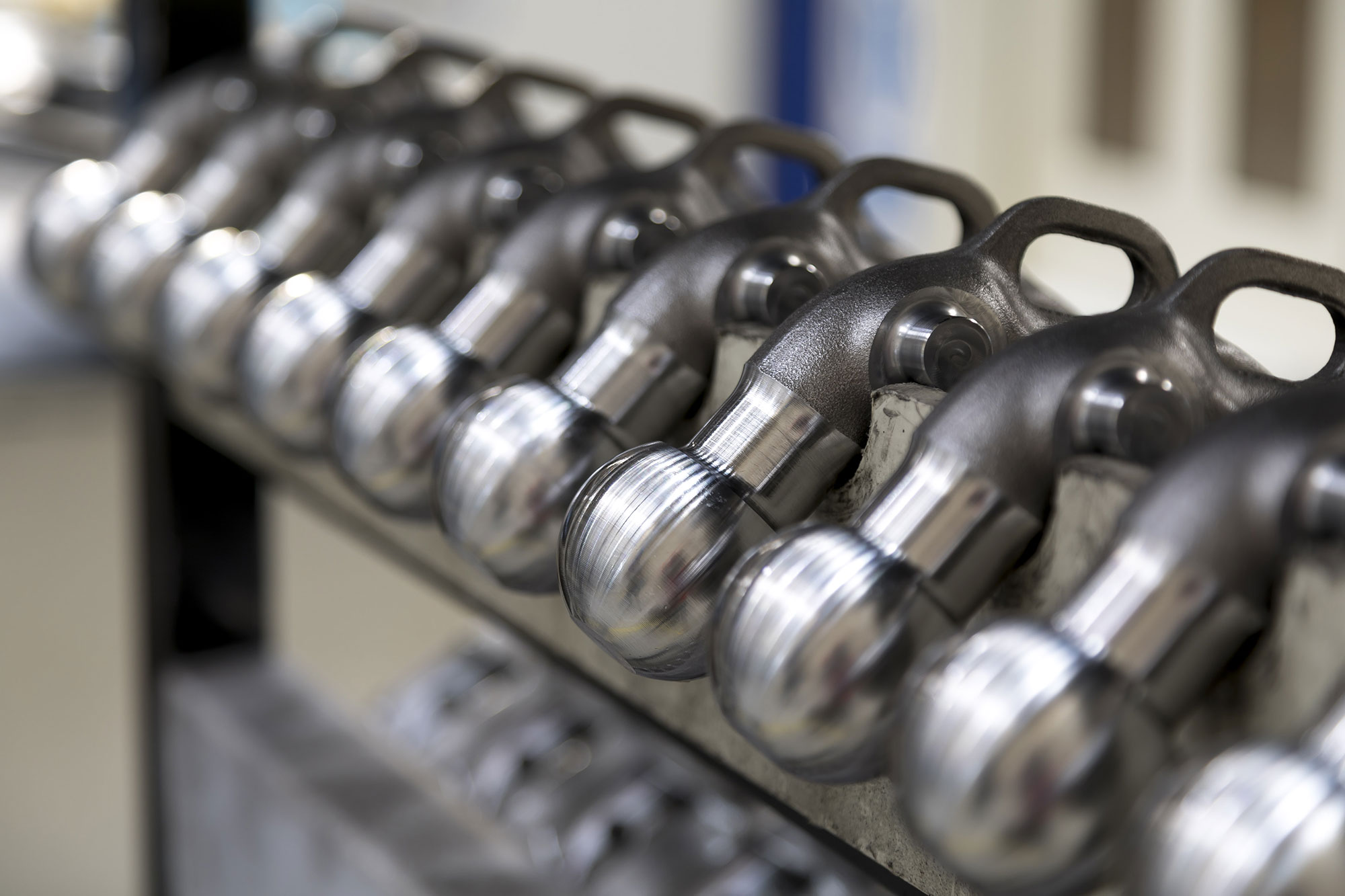 Row of forged ORIS towbar necks and towball components during precision manufacturing and quality control in production.