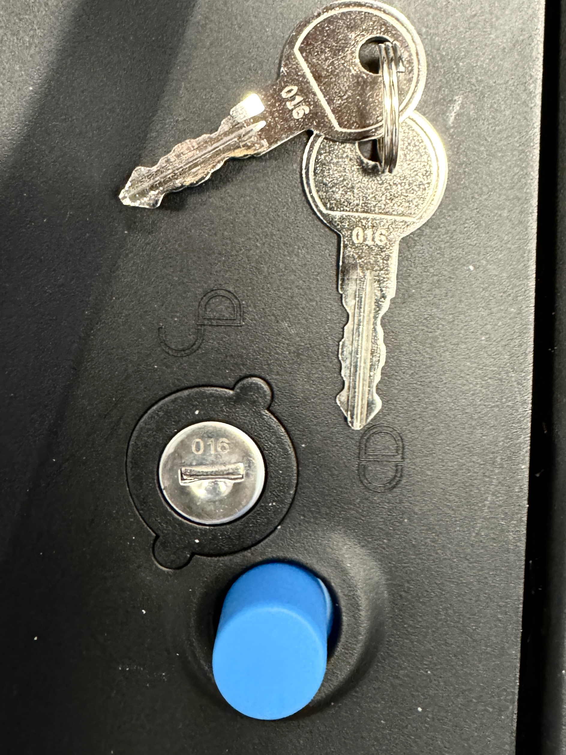 Close-up of the lock cylinder, matching keys and blue release button on an ORIS TRACC bike carrier locking mechanism.