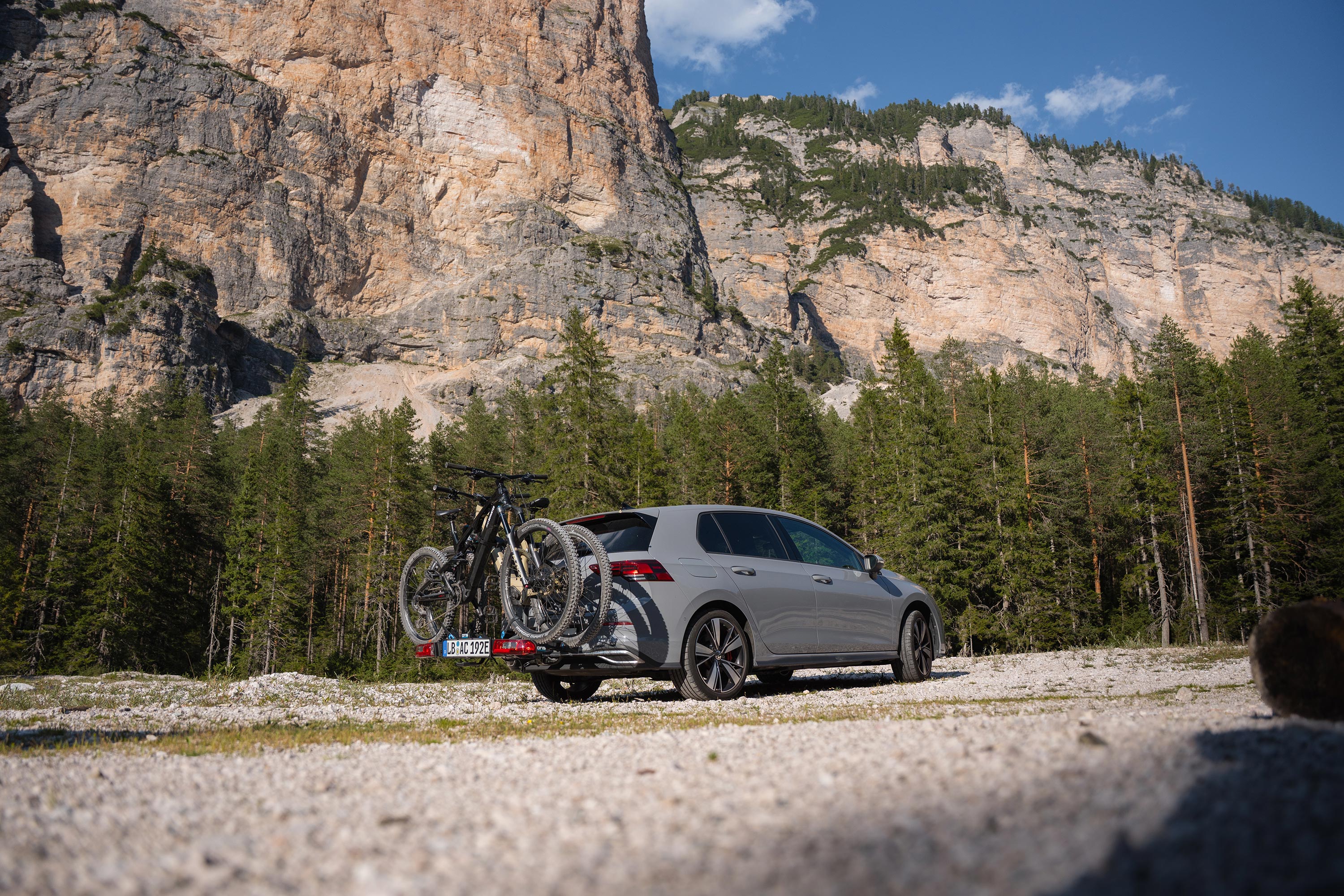 Grey Volkswagen Golf 8 with an ORIS bike carrier transporting two e-mountain bikes in a mountain landscape.