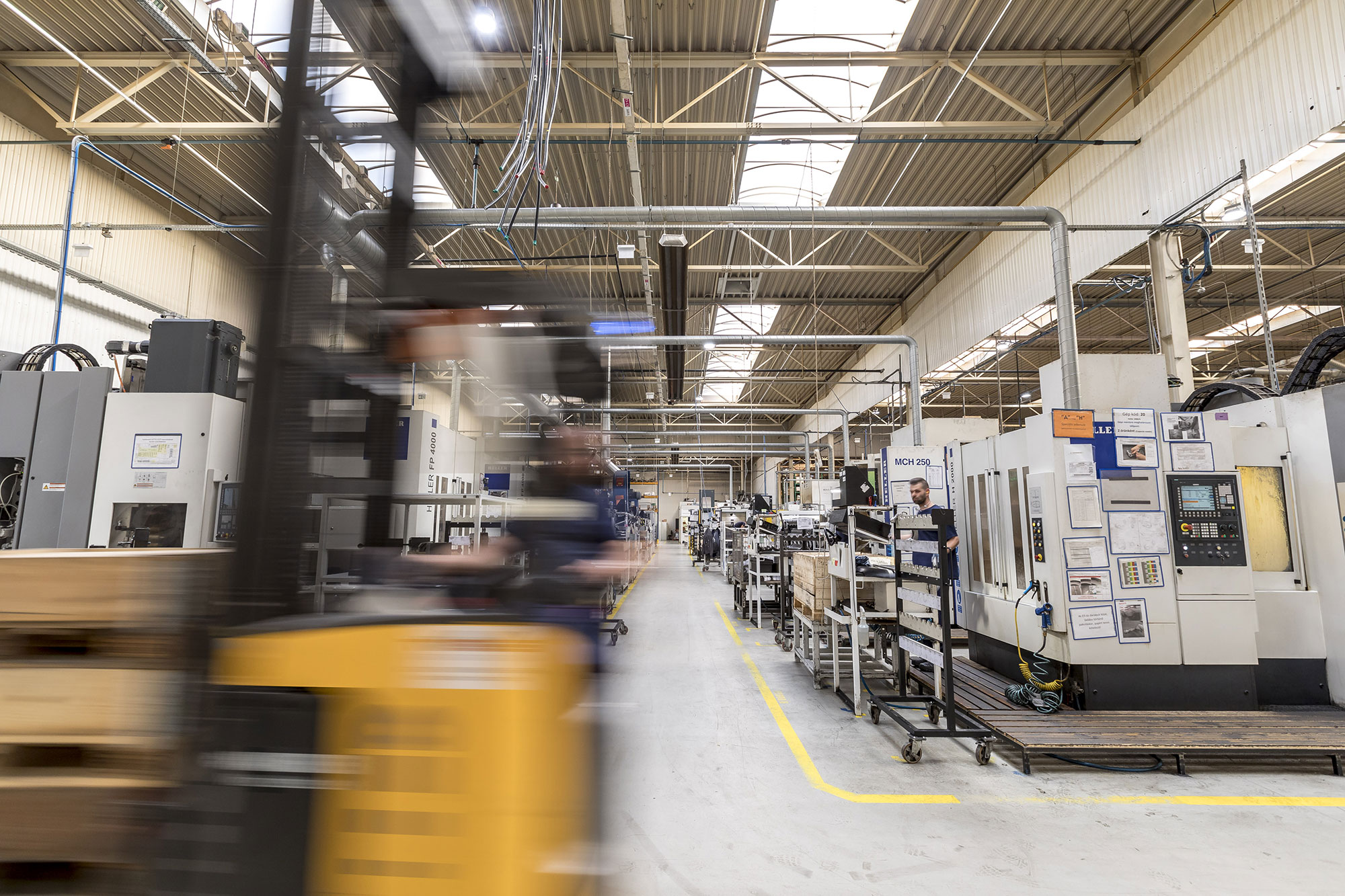 Modern ORIS production facility with CNC machining centres, industrial manufacturing equipment and forklift transport in automotive component production.