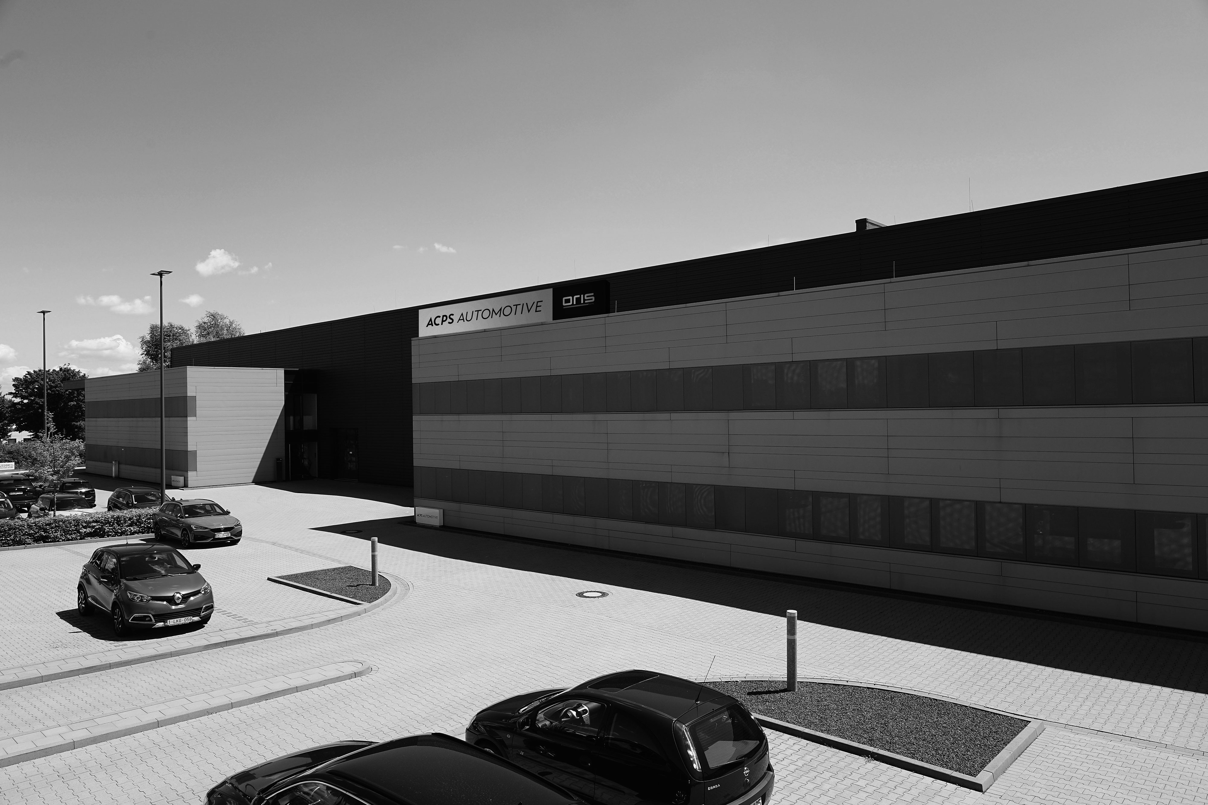Schwarz-Weiß-Aufnahme des ACPS Automotive Aftermarket Hauptsitzes in Mönchengladbach mit modernem Logistik- und Bürogebäude.