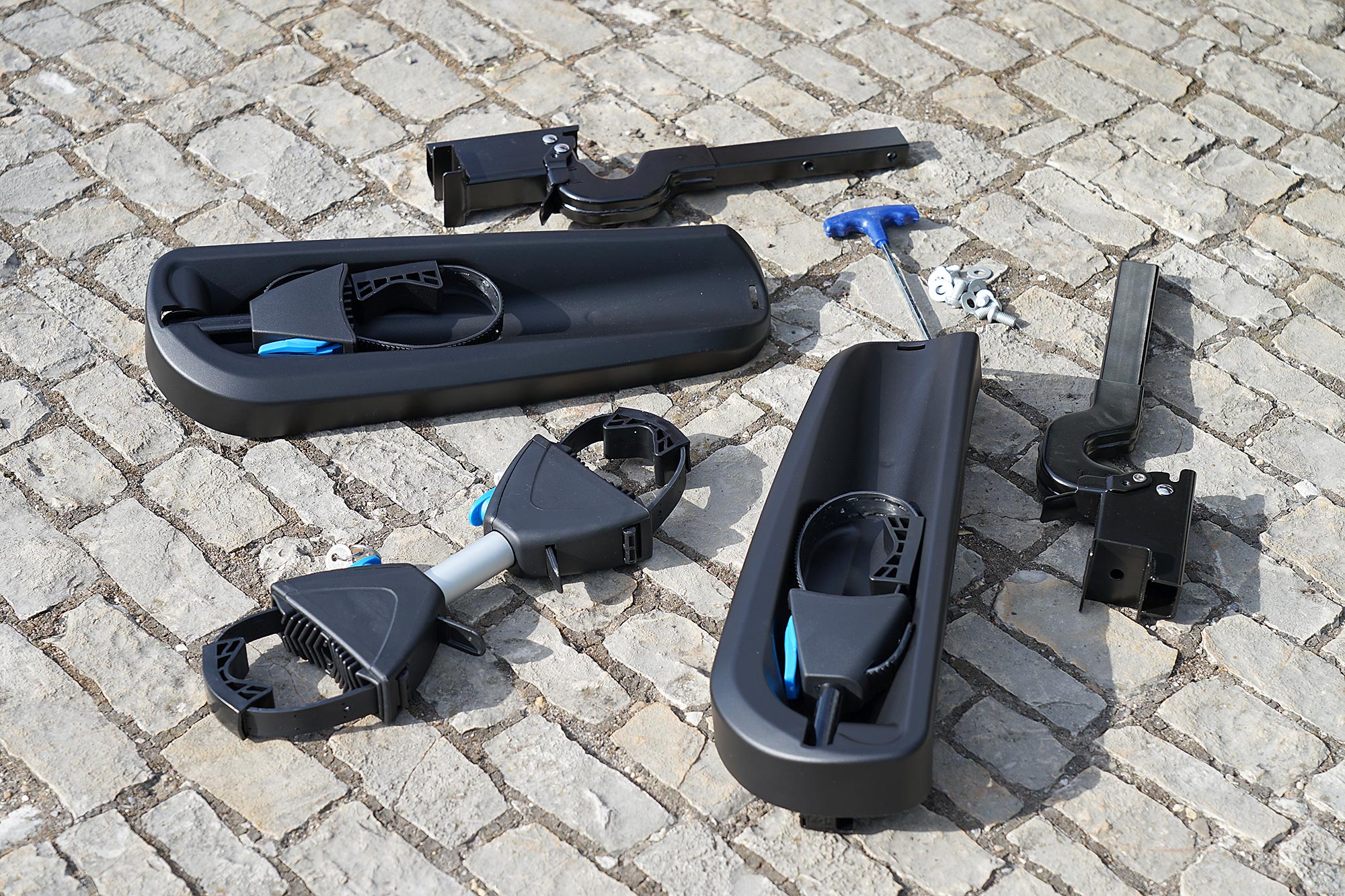 ORIS TRACC spare parts kit with frame holders, wheel straps, mounting brackets, screws and assembly tool on cobblestone surface.