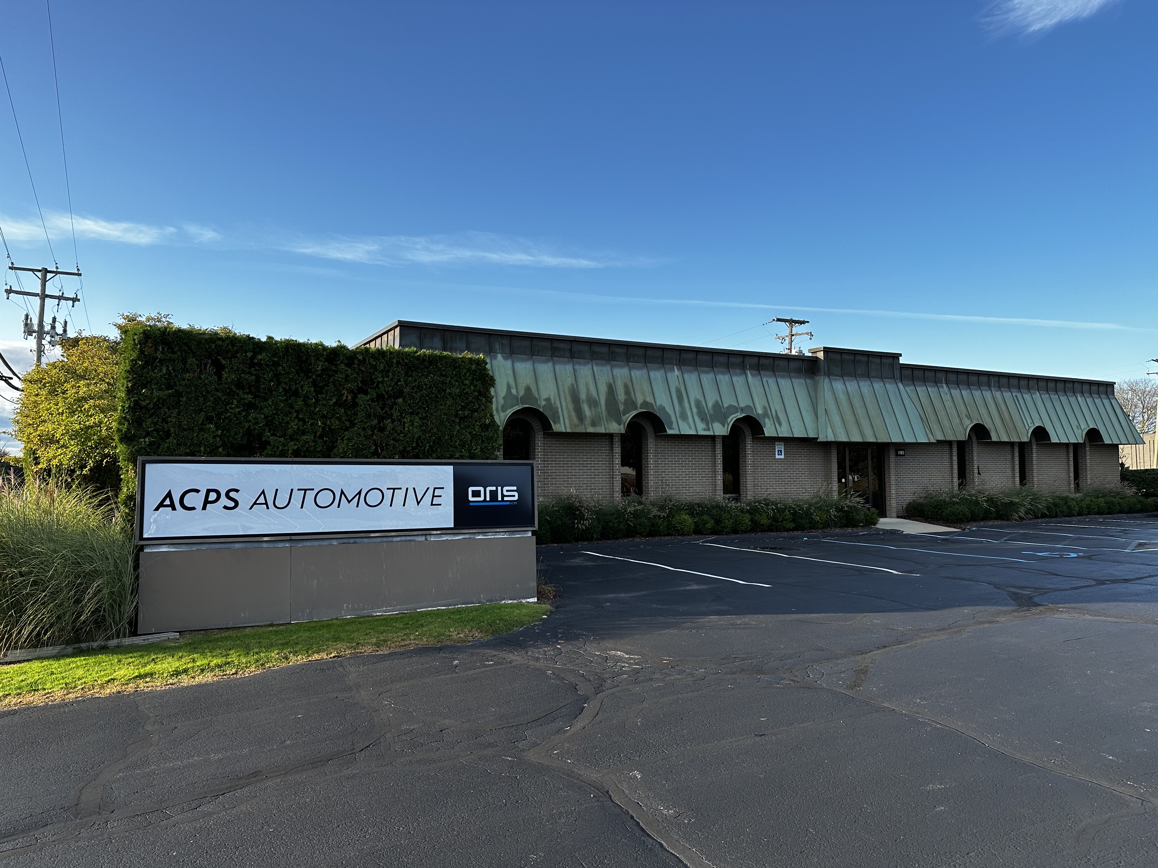 ACPS Automotive building at the US location with ORIS sign, parking lot and blue sky.