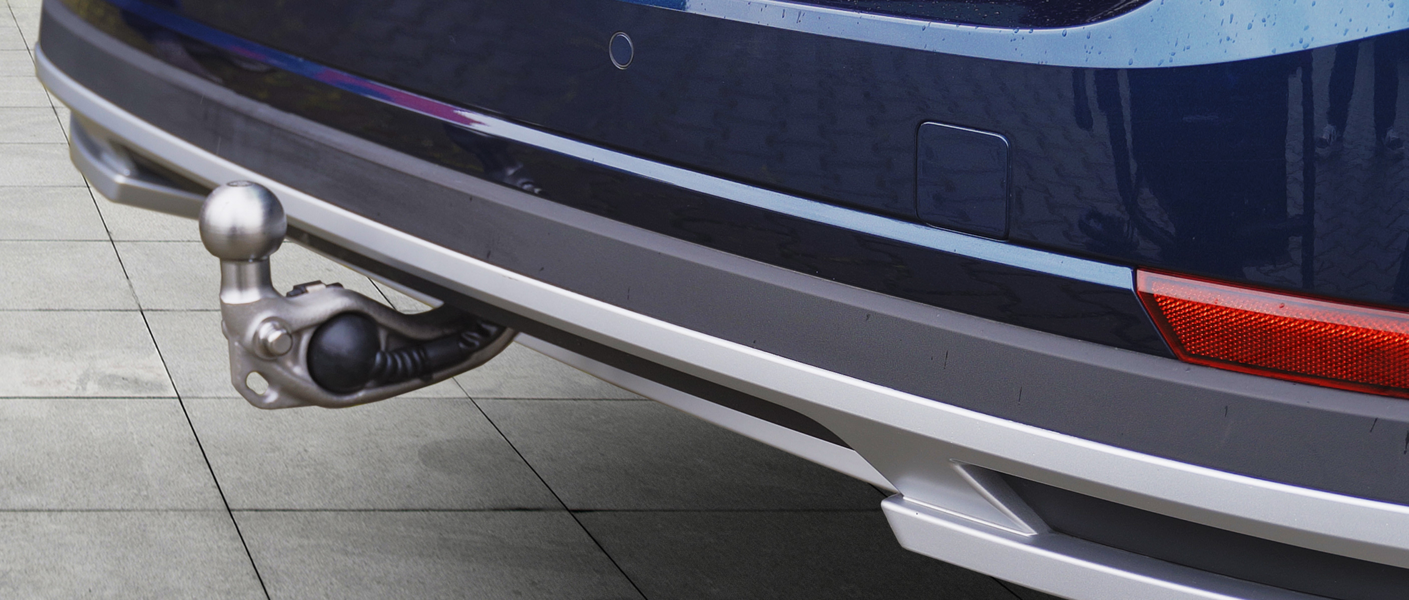 Side close-up of the ORIS E3 electric swivelling towbar in the deployed position on a dark blue Škoda SUV.