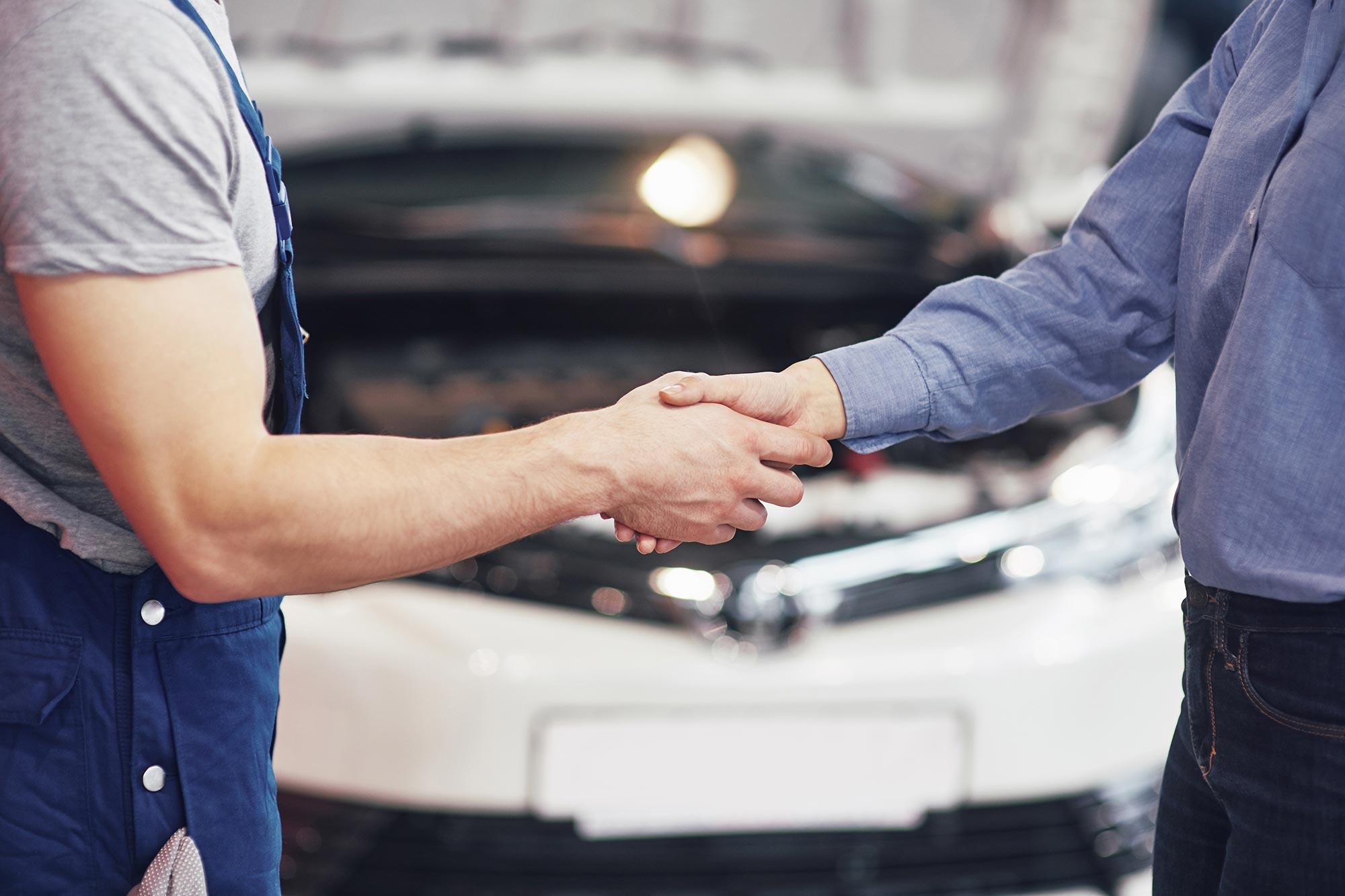 Customer and workshop technician shaking hands in front of a vehicle after successful ORIS towbar installation.