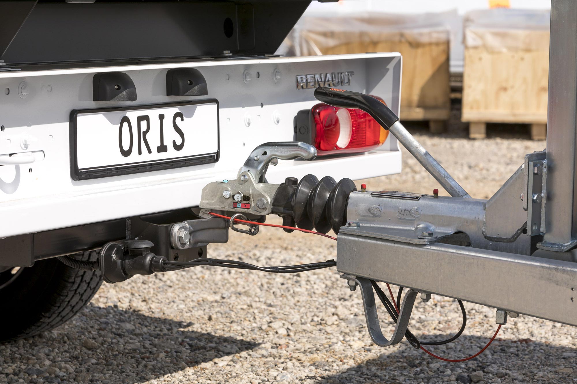 Close-up of an ORIS flanged towbar with fixed towball and electrical connection coupling a trailer to the rear of a Renault truck.