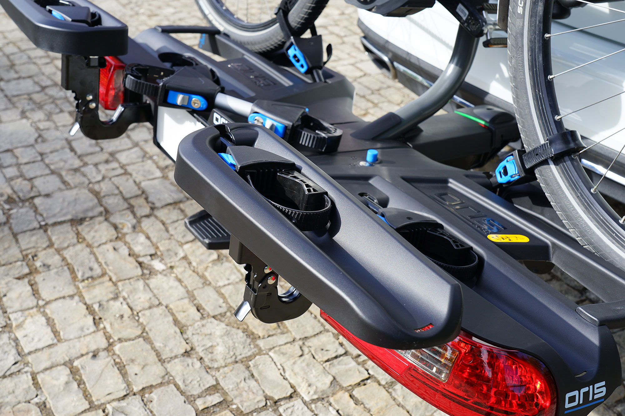 Close-up of the ORIS TRACC FIX4BIKE extension rail with integrated wheel straps and bicycle wheel mounted on the rear bike carrier.